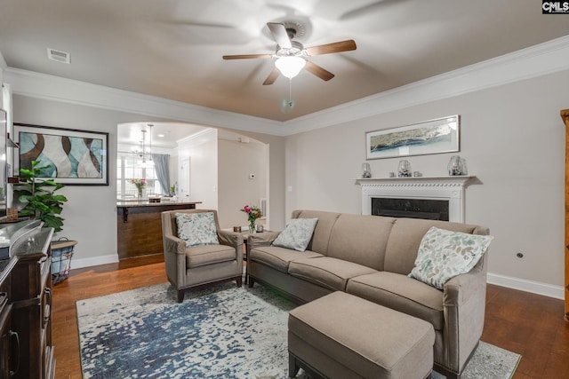 living room featuring arched walkways, a fireplace, visible vents, ornamental molding, and dark wood finished floors