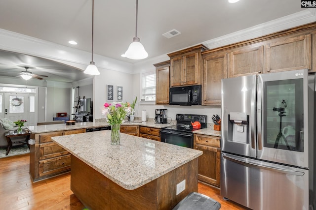 kitchen with visible vents, ornamental molding, a center island, a peninsula, and black appliances