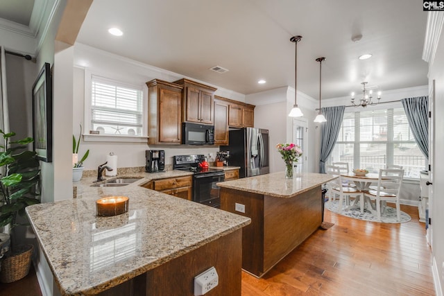 kitchen with light wood-style flooring, a sink, visible vents, a kitchen island, and black appliances