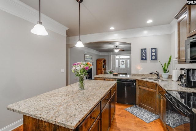 kitchen with arched walkways, a sink, a kitchen island, light wood-type flooring, and black appliances