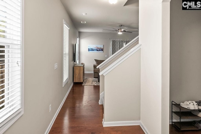 hallway featuring stairway, dark wood-style flooring, visible vents, and baseboards