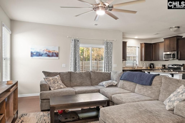 living room with light wood-type flooring, baseboards, and a ceiling fan