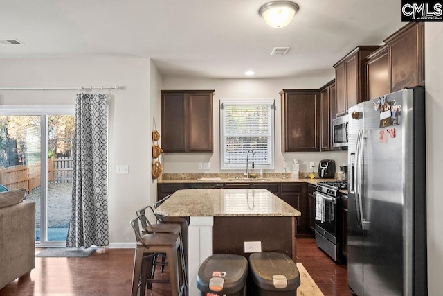 kitchen with dark brown cabinetry, a sink, visible vents, appliances with stainless steel finishes, and dark wood-style floors