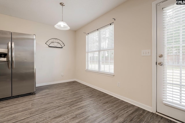 unfurnished dining area featuring wood finished floors and baseboards