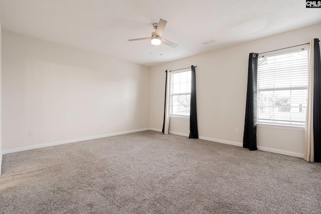 unfurnished room with carpet, visible vents, a ceiling fan, a textured ceiling, and baseboards