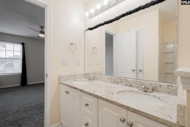 bathroom with double vanity, a ceiling fan, baseboards, and a sink