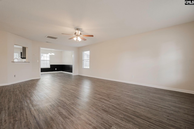 unfurnished living room featuring visible vents, baseboards, dark wood-style flooring, and ceiling fan with notable chandelier