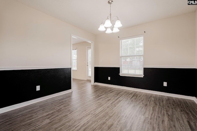 unfurnished room with a healthy amount of sunlight, baseboards, a chandelier, and wood finished floors