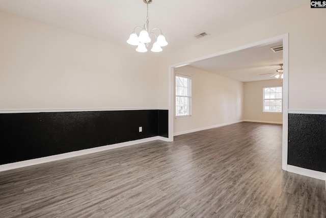 unfurnished room featuring baseboards, visible vents, wood finished floors, and ceiling fan with notable chandelier