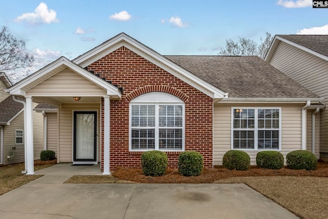 single story home featuring brick siding and roof with shingles