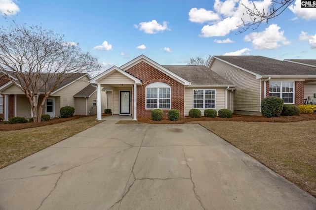 single story home featuring brick siding, a front yard, and a shingled roof