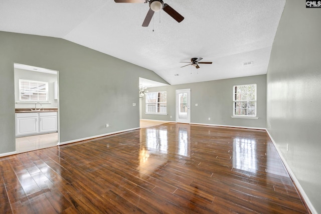 unfurnished living room with lofted ceiling, visible vents, hardwood / wood-style floors, a sink, and baseboards