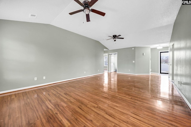 unfurnished living room with vaulted ceiling, wood finished floors, visible vents, and baseboards