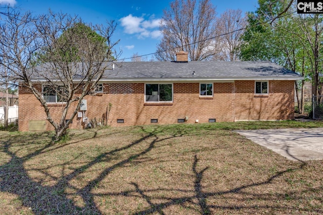 back of property featuring brick siding, a chimney, a lawn, crawl space, and a patio area