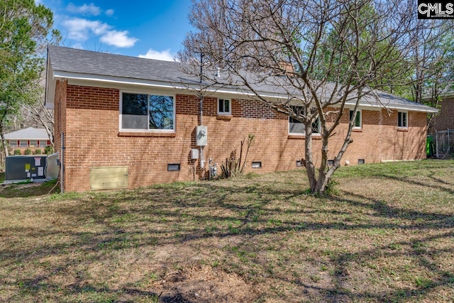 rear view of house featuring crawl space, brick siding, and a yard