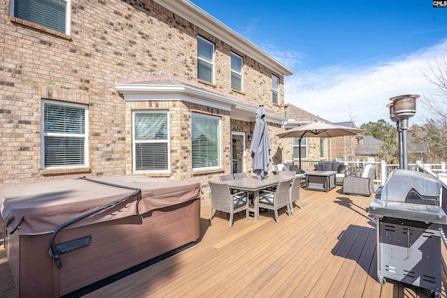 wooden deck featuring outdoor dining space, grilling area, and a hot tub