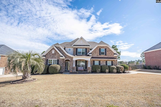 view of front facade featuring brick siding, a front yard, and fence