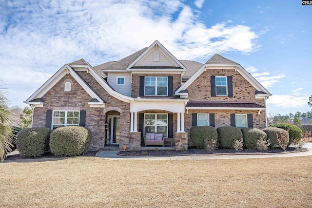 craftsman house with brick siding, a front lawn, and roof with shingles