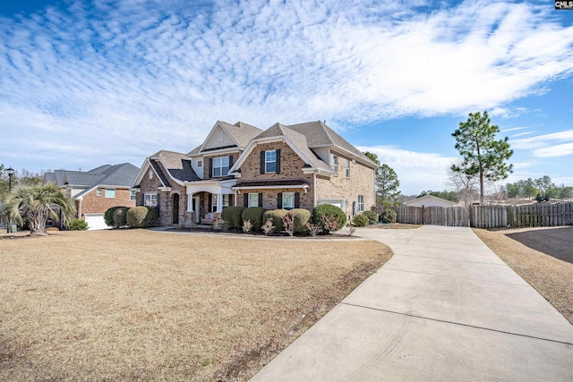 view of front facade featuring driveway, a front yard, fence, and brick siding