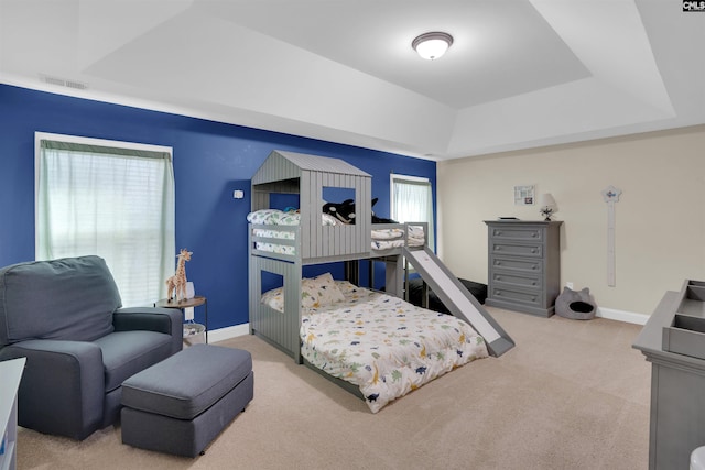 bedroom with baseboards, visible vents, a tray ceiling, and carpet flooring