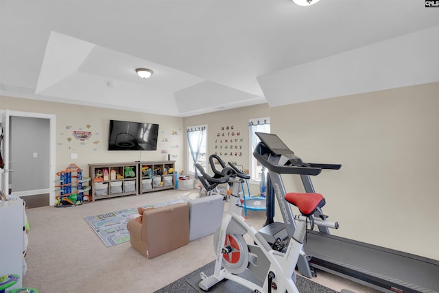 exercise room featuring carpet and a raised ceiling