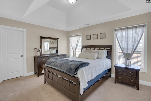 bedroom with baseboards, a tray ceiling, visible vents, and light colored carpet