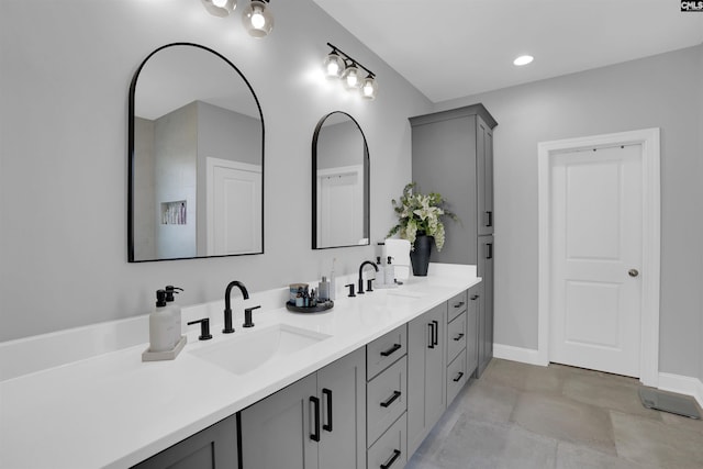 full bath with double vanity, a sink, and baseboards