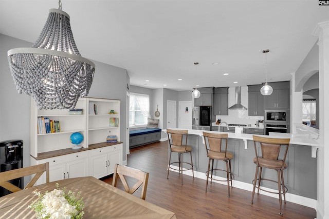 kitchen featuring black microwave, arched walkways, oven, gray cabinets, and wall chimney exhaust hood