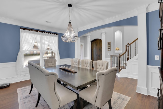 dining space featuring visible vents, arched walkways, dark wood-style floors, a wainscoted wall, and ornate columns