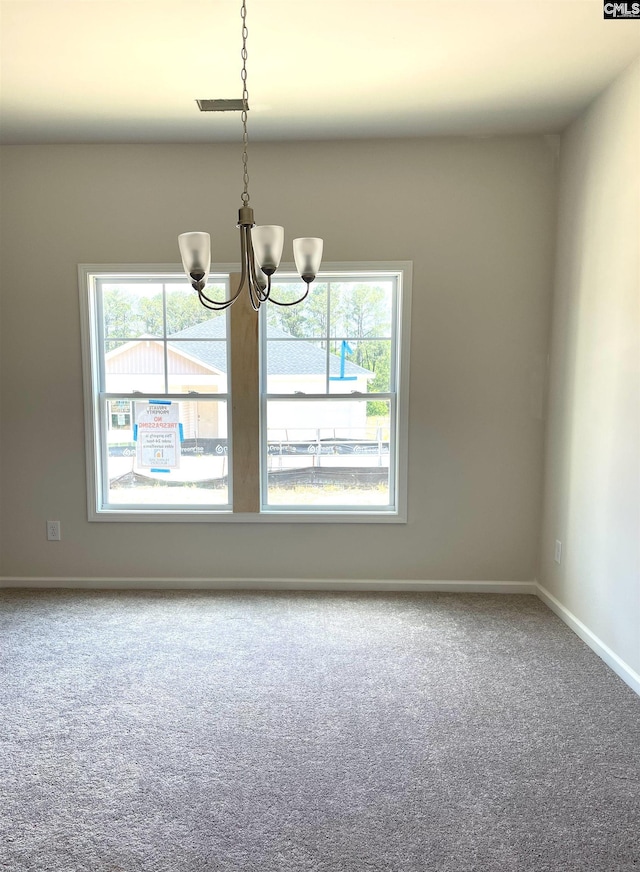 empty room with carpet flooring, baseboards, and an inviting chandelier