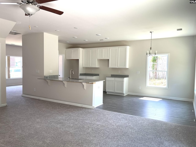kitchen featuring stone countertops, a kitchen bar, white cabinetry, and a sink