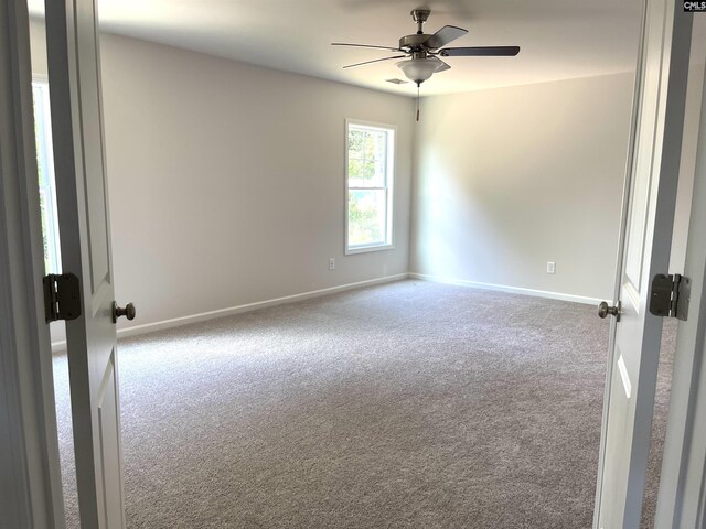 carpeted empty room featuring ceiling fan and baseboards