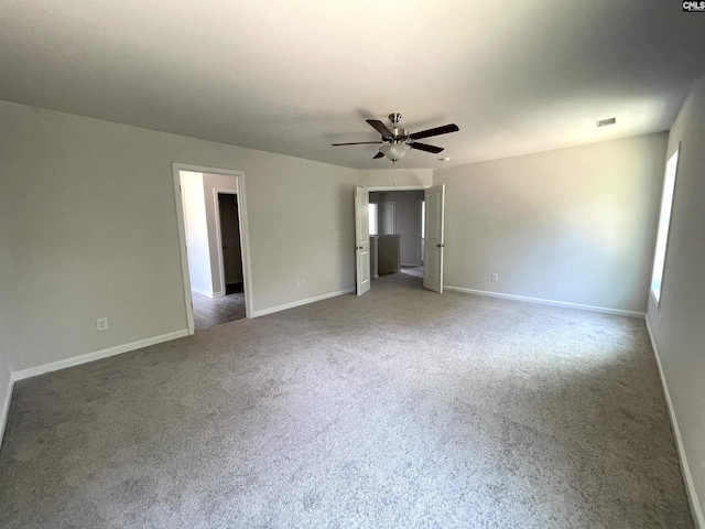 carpeted empty room with visible vents, baseboards, and a ceiling fan