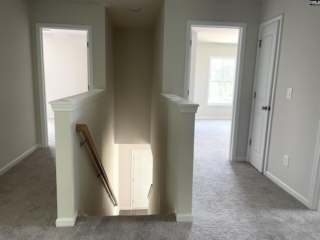 hallway with carpet, an upstairs landing, and baseboards