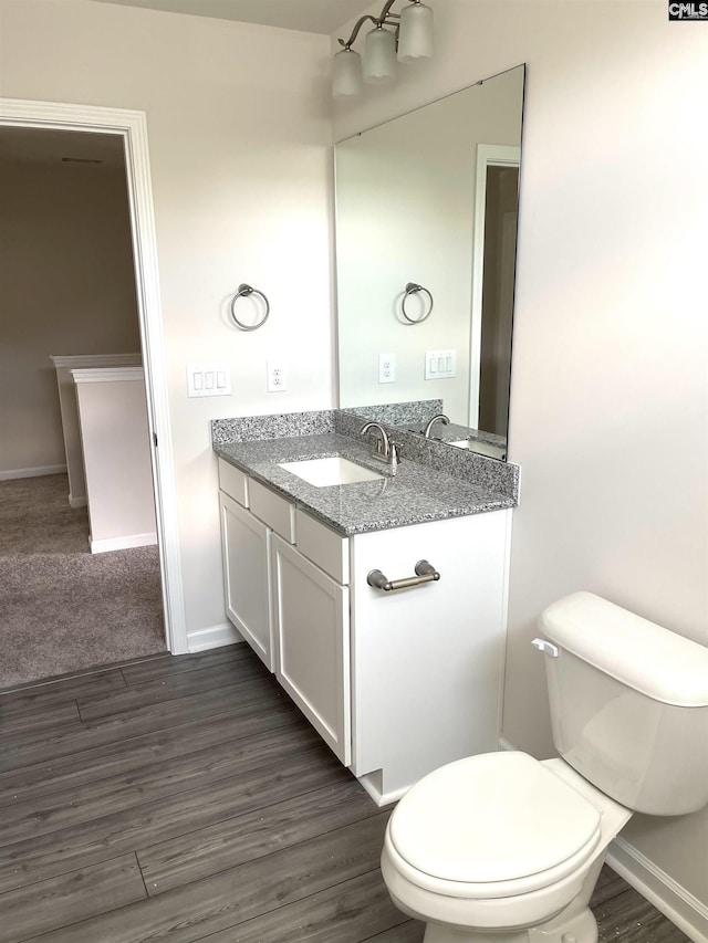 bathroom with toilet, baseboards, wood finished floors, and vanity