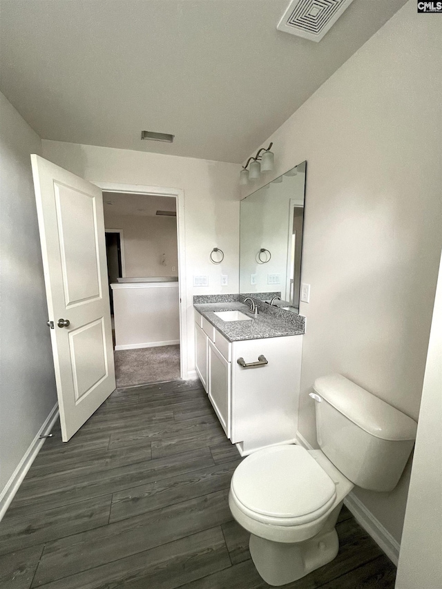 bathroom featuring visible vents, vanity, toilet, and wood finished floors