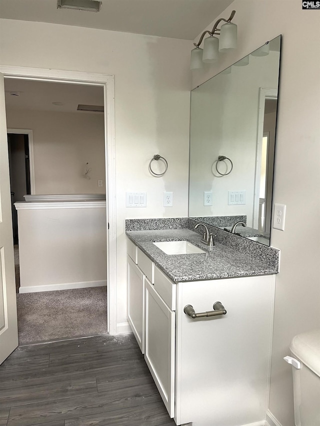 bathroom with toilet, wood finished floors, vanity, and baseboards