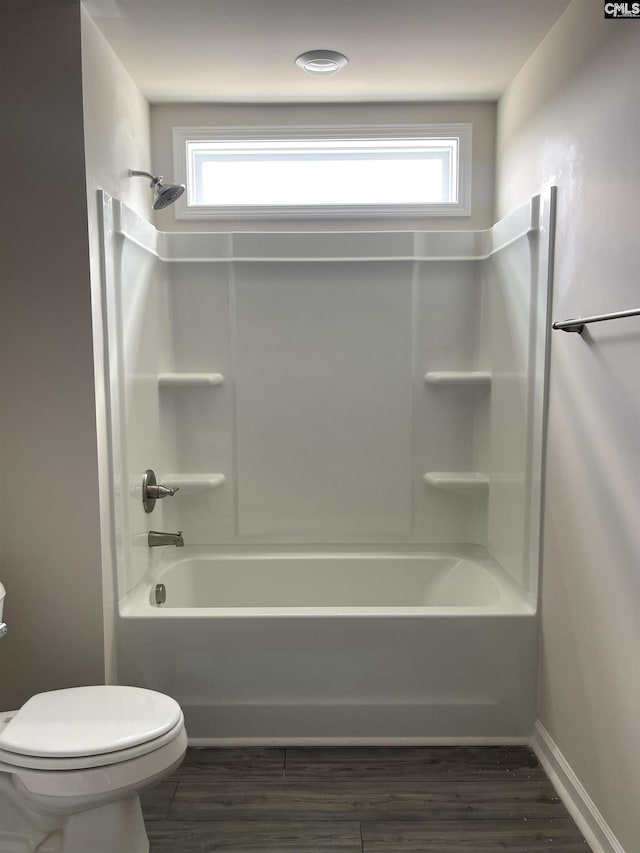 bathroom featuring bathtub / shower combination, a healthy amount of sunlight, toilet, and wood finished floors