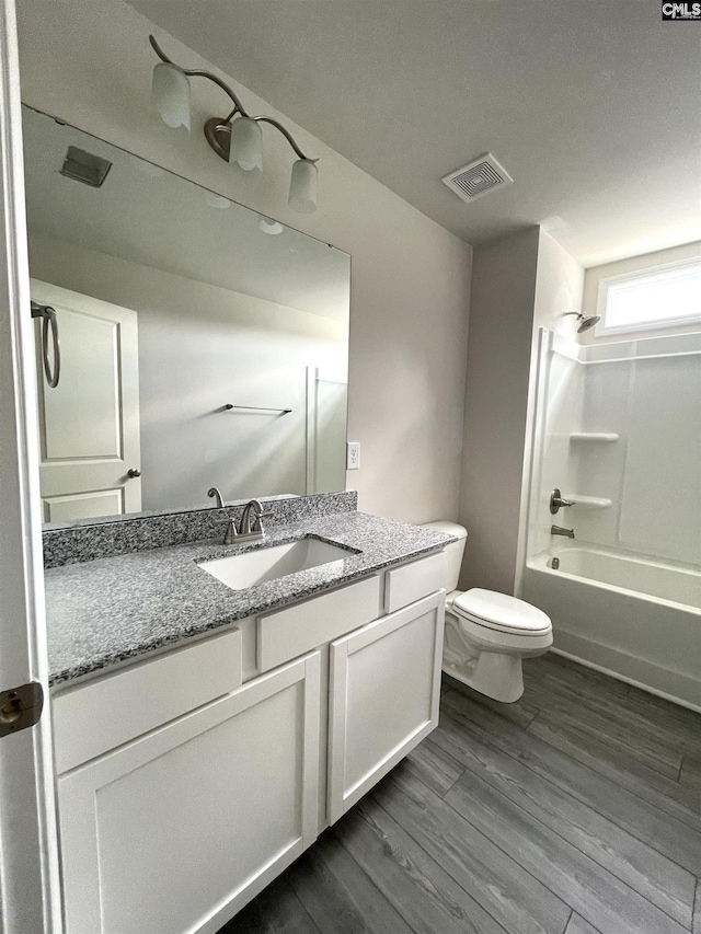 full bathroom featuring visible vents, toilet, wood finished floors, vanity, and shower / bathing tub combination