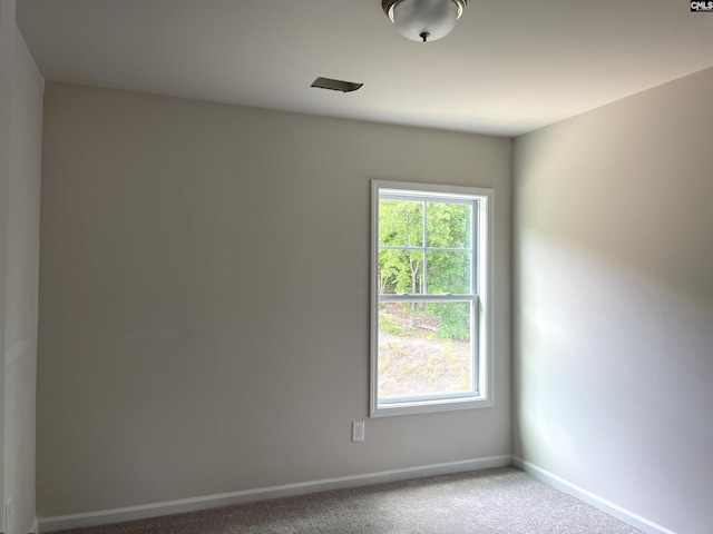 carpeted spare room featuring a healthy amount of sunlight and baseboards