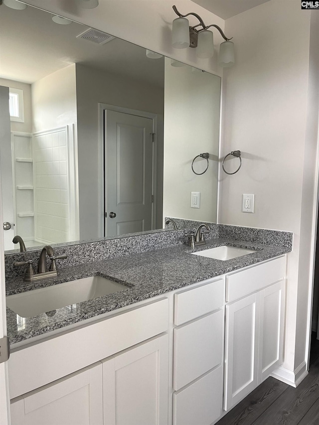 full bath featuring double vanity, visible vents, a sink, and wood finished floors