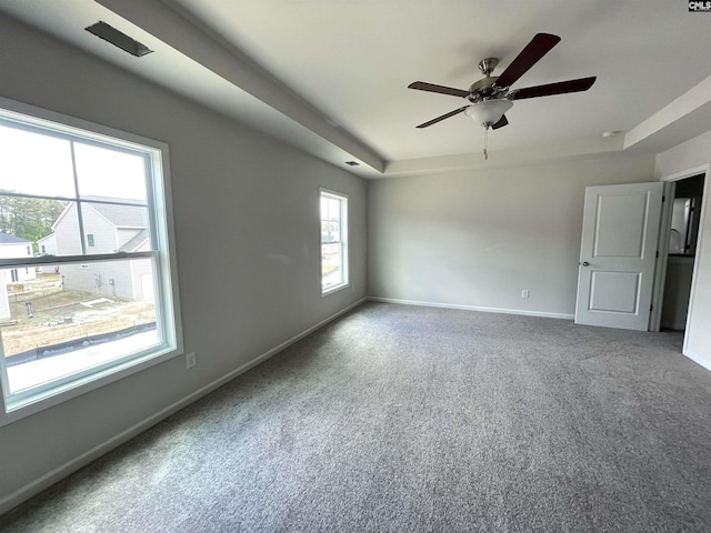 spare room featuring a ceiling fan, carpet, a tray ceiling, and baseboards