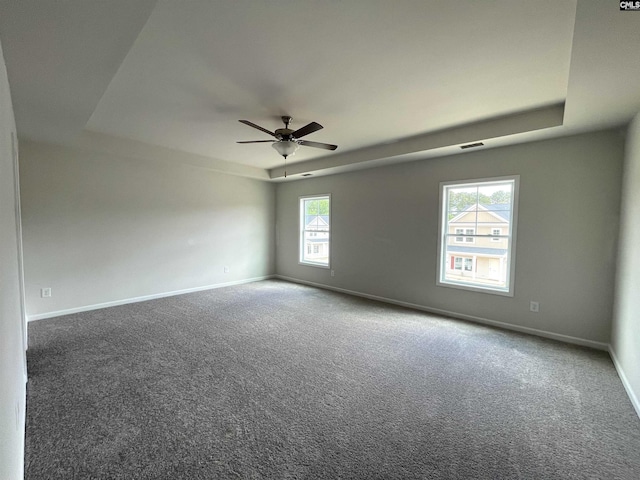 carpeted spare room featuring ceiling fan, baseboards, and a raised ceiling