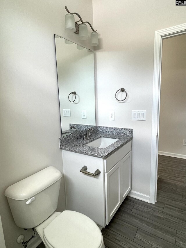 bathroom with toilet, baseboards, wood finished floors, and vanity