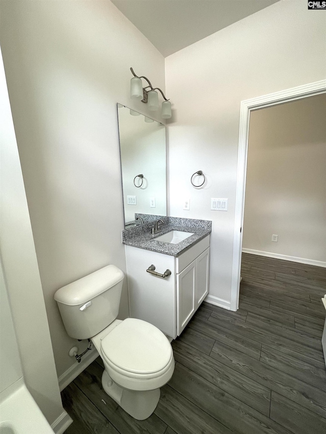 bathroom with baseboards, vanity, toilet, and wood finished floors