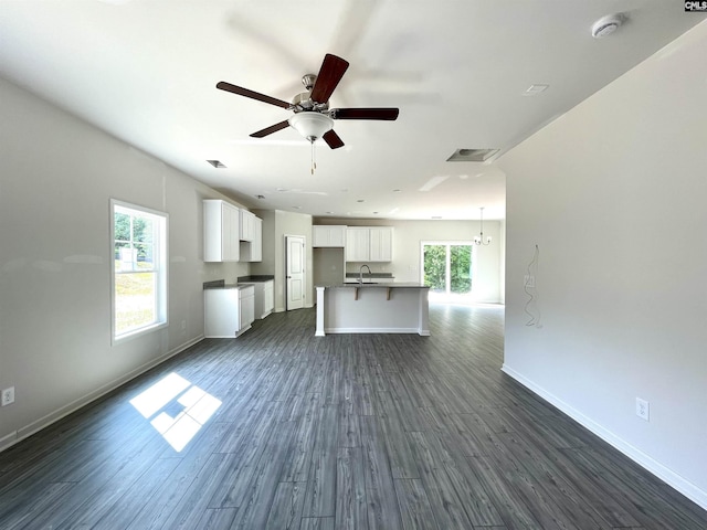 unfurnished living room featuring a ceiling fan, a sink, dark wood finished floors, and baseboards