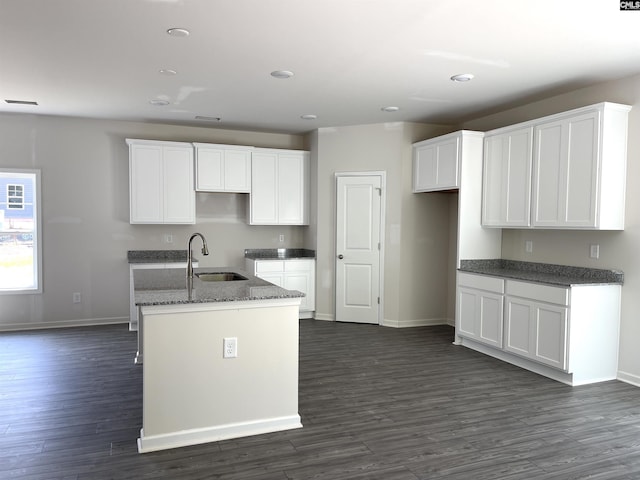 kitchen with an island with sink, white cabinetry, dark wood-style flooring, and a sink