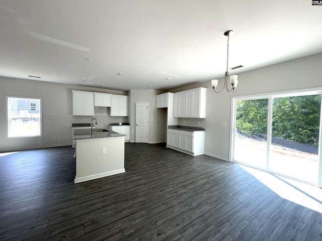 kitchen with dark wood-type flooring, a sink, white cabinets, and an inviting chandelier