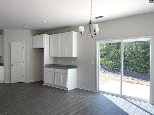 kitchen with baseboards, white cabinets, dark countertops, dark wood-type flooring, and a notable chandelier