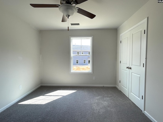 unfurnished bedroom featuring carpet flooring, a ceiling fan, visible vents, baseboards, and a closet